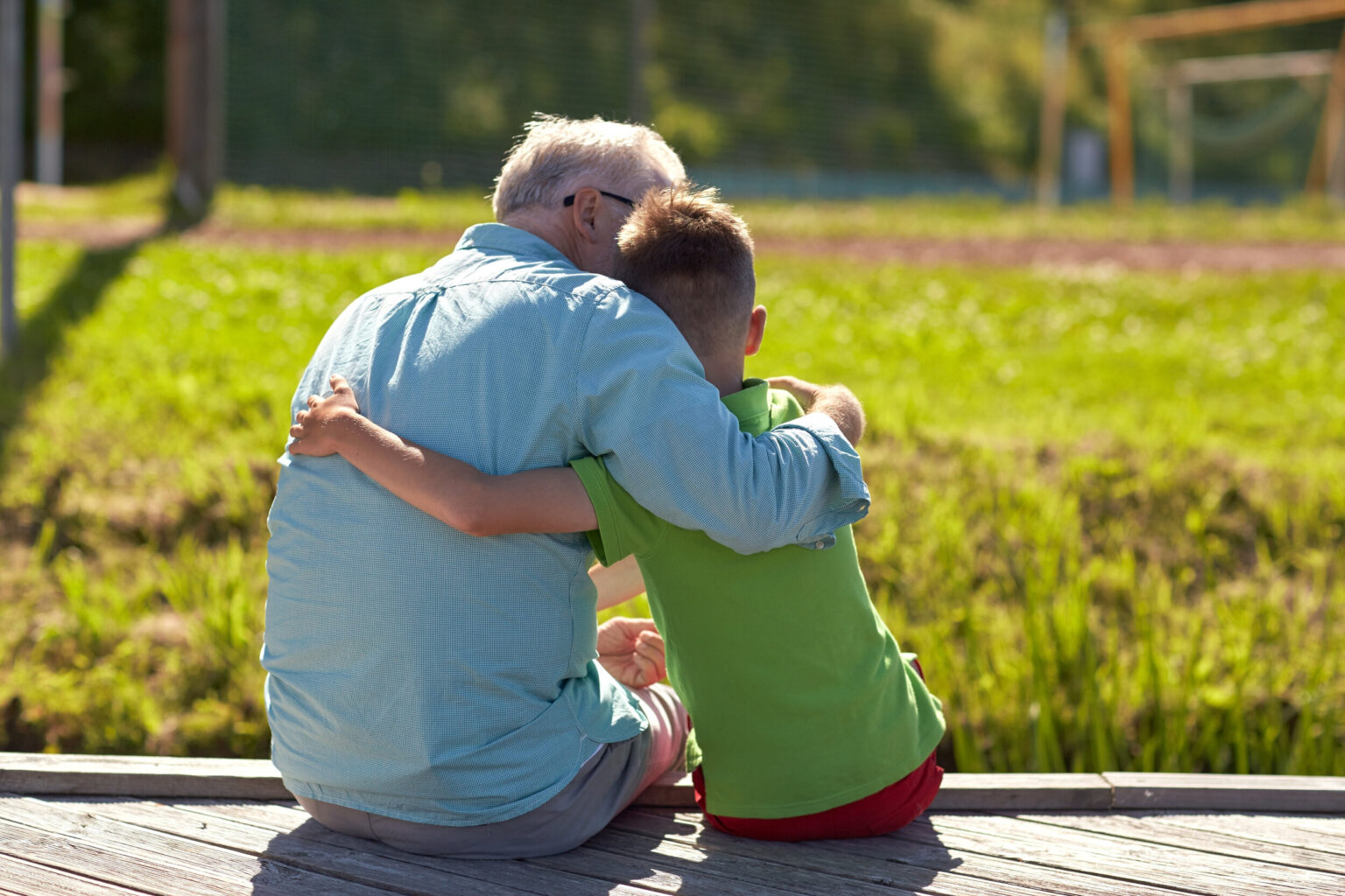 family, generation, relations and people concept - happy grandfather and grandson hugging on berth