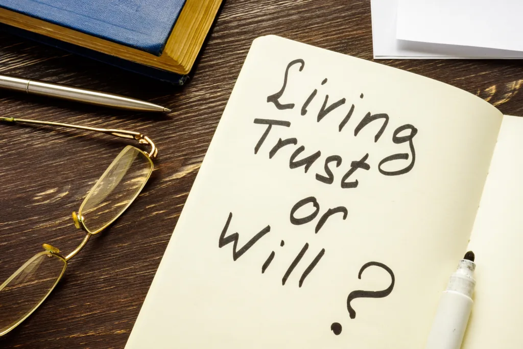 Notebook reading “Living Trust or Will” on a desk with glasses and a pen.